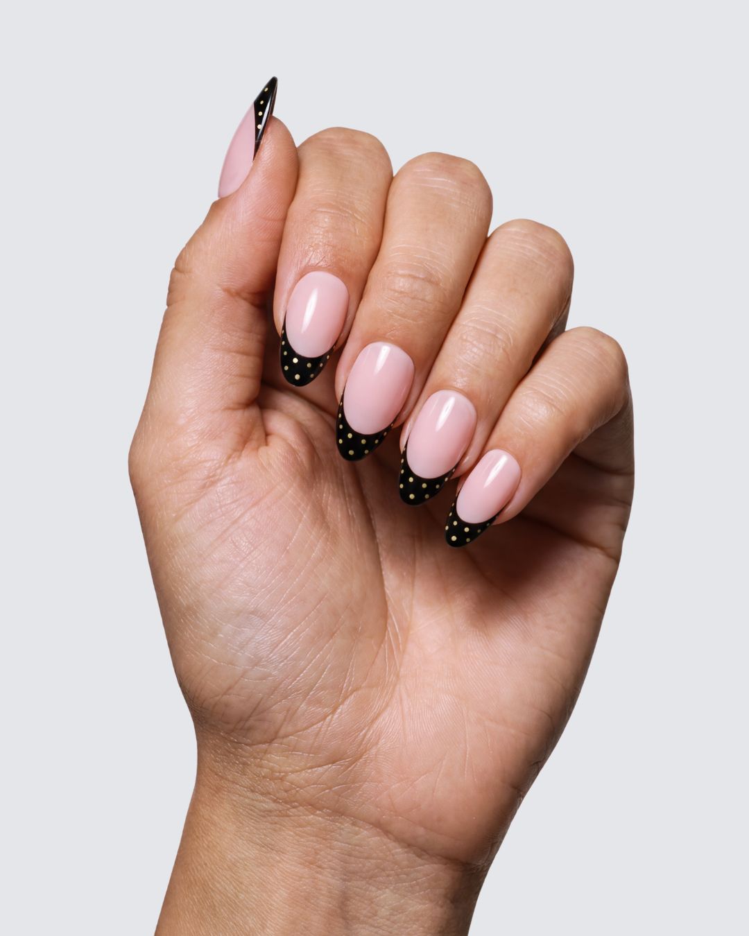 Coco Noir press on nails, pink nude almond with a glossy black french tip and tiny gold dots